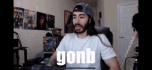 a man with long hair and a hat is sitting in front of a microphone with the word gonb on the screen