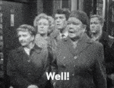 a group of people are standing in front of a building and one of them is saying well
