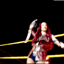 a woman with red hair is holding a trophy in a wrestling ring .