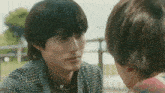 a man in a plaid coat is looking at another man 's face