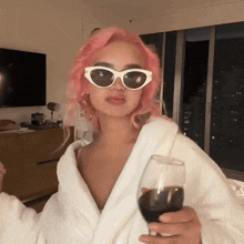 a woman with pink hair is wearing sunglasses and holding a wine glass