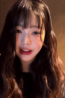 a young girl with long hair and bangs is looking at the camera .