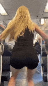 a woman in a black tank top and shorts is standing on a train