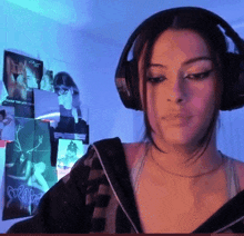 a woman wearing headphones stands in front of a wall with posters on it including one that says freak