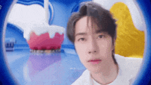 a close up of a person 's face with a cake in the background