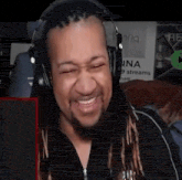 a man with dreadlocks is wearing headphones and smiling while looking at the camera .