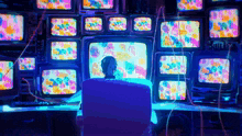 a man is sitting in front of a bunch of monitors with a colorful background