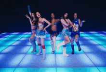 a group of women are dancing on a dance floor with blue lights