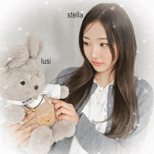 a girl holding a stuffed animal with the name lusi written on the bottom