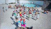 a group of people are dancing in front of a pool with a man wearing a headband with the letter a on it