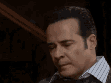 a close up of a man 's face with his eyes closed and a striped shirt .