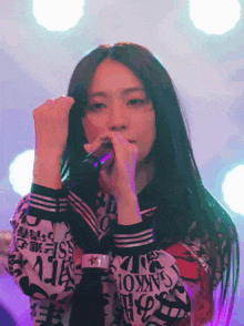 a woman singing into a microphone with a shirt that says " sankoi " on it