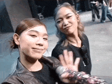 two women are standing next to each other on a sidewalk .