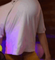 a man wearing a white shirt and yellow shorts is standing in front of a purple light .