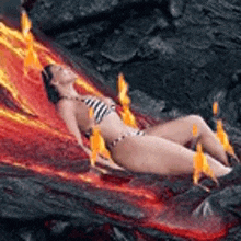 a woman in a bikini is laying in a pool of lava .