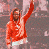 a man in a red hoodie is singing into a microphone in front of a crowd .