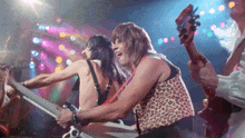 a man in a leopard print vest is playing a guitar in a band
