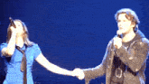 a man and a woman holding hands on a stage