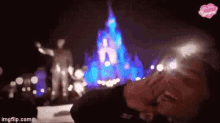 a person is laying on the ground in front of a castle at night .