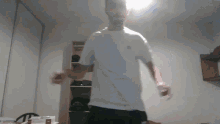 a man in a white shirt and black shorts is dancing in a room