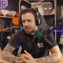a man wearing headphones and a shirt that says santa cruz talks into a microphone