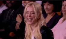 a woman is laughing while sitting in a crowd .
