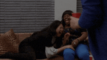 a group of women are sitting on a couch laughing
