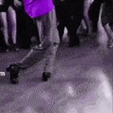 a man in a purple shirt is dancing in front of a crowd of people on a dance floor .