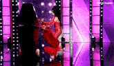 a woman in a red dress is standing in front of a black coffin .