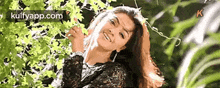 a woman in a black lace top is standing in front of a waterfall .