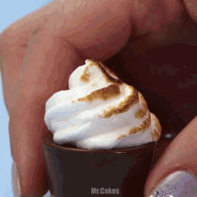 a person is holding a shot glass with whipped cream and marshmallows on top of it and the words mr.cakes on the bottom