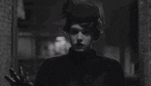 a black and white photo of a man in a trench coat walking down a dark alleyway .