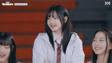 a girl in a white shirt and tie smiles in front of a sign that says run up