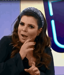 a woman wearing a headband with rhinestones is talking on a television show .