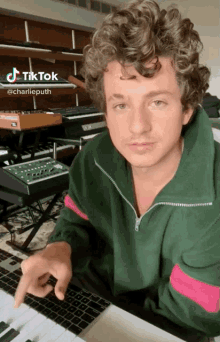 a man with curly hair is sitting in front of a keyboard with a tiktok sticker on the bottom right