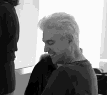 a black and white photo of a man with white hair laughing .
