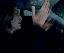 a woman is sitting in a car with a sun visor that says ' warning ' on it