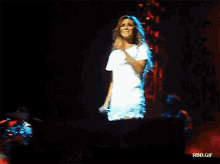a woman singing into a microphone on a stage with rbd.gif at the bottom