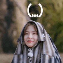 a woman wearing a plaid shirt with a hood and a smiley face on her head