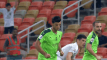 a soccer player wearing a green qatar jersey is running