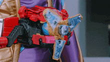 a person wearing a purple and gold outfit is holding a toy that looks like a transformer