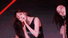 a woman is singing into a microphone while another woman looks on .