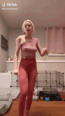 a woman is dancing in a room with a dog cage in the background .