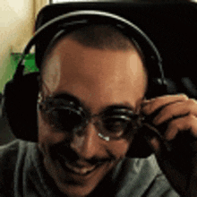 a man wearing glasses and headphones is smiling and looking at the camera .