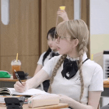 a girl in a school uniform is sitting at a desk in a classroom with a pen in her hand .