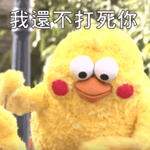 a stuffed yellow bird with chinese writing on it 's face .