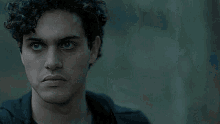 a young man with curly hair and blue eyes is looking at the camera .