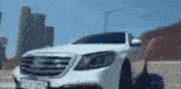 a white car is parked on the side of the road in front of a city skyline .