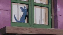a blue cat is looking out of a window with a green frame .