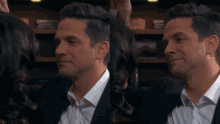 a man in a suit and a woman in a white shirt look at each other